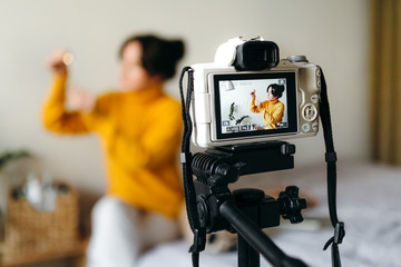 Young brunette girl beauty blogger is showing how to serum for skin care on camera. Concept of filming a blog. Beauty and skin care.