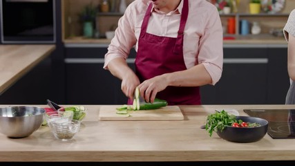 Cooking show host celebrity chef shows hot to cut cucumber, broadcast TV programme. Shot on ARRI Alexa Mini
