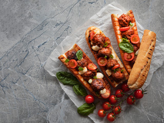 sandwich with meatballs on a baguette, with melted cheese, tomato sauce, parsley and Parmesan...