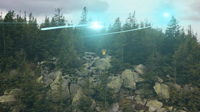 Visualization of Information Flows and Lines Flying from Mobile Phone into Global Network. Aerial Drone Shot. young woman standing on on a rock on top of a mountain