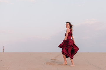 Girl in red dress with cloth in the wind in the desert