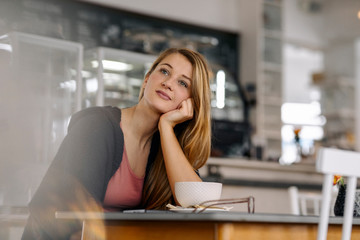 Portrait of daydreaming young woman in a cafe
