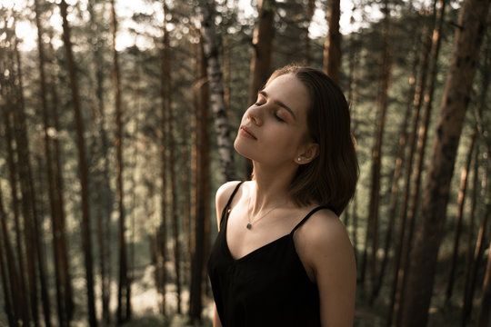 portrait of a girl with closed eyes in the middle of the forest, enjoys the fresh forest air