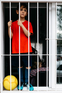 Boy with soccer ball at the window without being able to leave the house to play