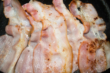 Fried slices of raw bacon. Close up.