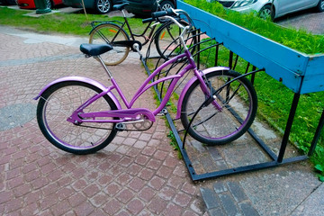 Fototapeta na wymiar A beautiful lilac bike for women stands on a sidewalk paved with a decorative stand in the rain. Street parking for cycling in the city. Close-up.