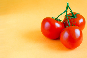 three ripe round red tomatoes in a bunch on a yellow background. red vegetables
