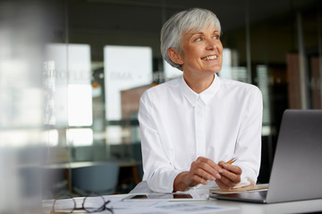 Portrait of smiling senior businesswoman at desk in her office