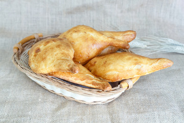   Uzbek samsa from puff pastry with filling in a wicker basket on a background of burlap