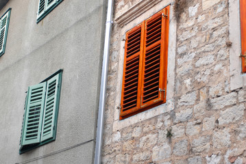 old fashioned window with red and green shutters