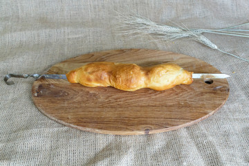 Asian skewers of samsa puff pastry on a skewer on a round kitchen board on a background of burlap