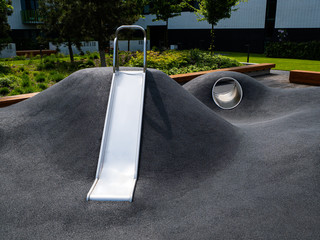 Modern playground with a metal slide inscribed in the landscape design. Playground without children.