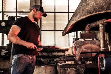 Knife maker working with damask steel at forging furnace