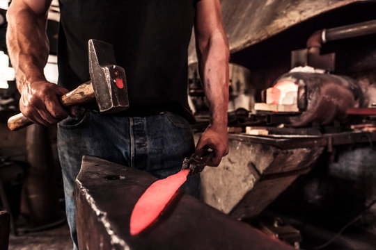 Knife maker at work, steel splinter during hammering damask steel