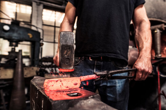 Knife maker working scattering borax over hot damask steel