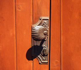 Antique doorknob on a wooden door, closeup. Antique metal door handle. Old wooden entrance door with antique door handle.
