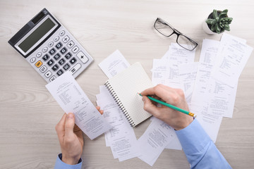 Naklejka na ściany i meble Unrecognizable businessman using calculator on desk office and writing make note with calculate about cost at home office. finance accounting concept. tax , shopping, cost management