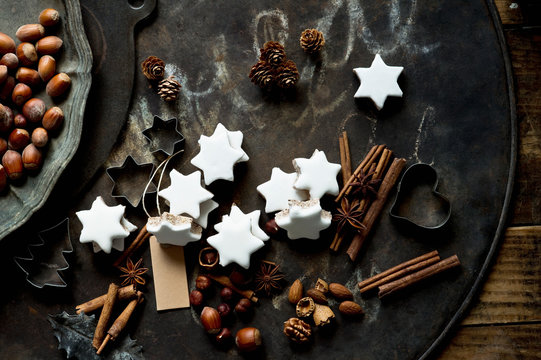 Rustic baking sheet, cinnamon sticks, star shaped Christmas cookies, cookie cutters and nuts