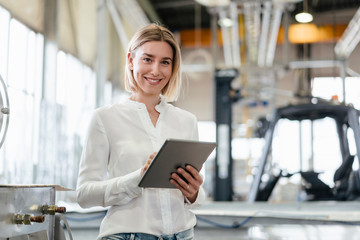 Portrait of smiling young woman using tablet in a factory