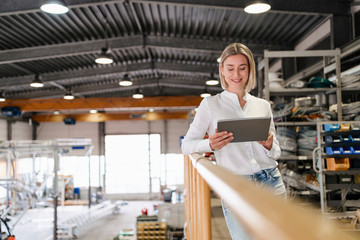 Smiling young woman using tablet in a factory
