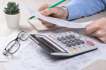 Unrecognizable businessman using calculator on desk office and writing make note with calculate...
