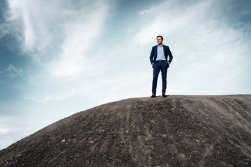 Mature businessman standing on top of a disused mine tip