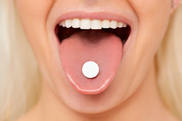 Beautiful woman mouth with pill on tongue. Girl taking medicine
