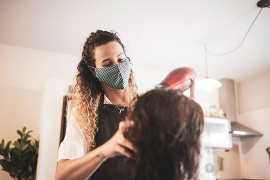 Hairdresser using face mask for the covid-19, new normality, social distance, hairdresser and client at client's home with mask cutting hair.