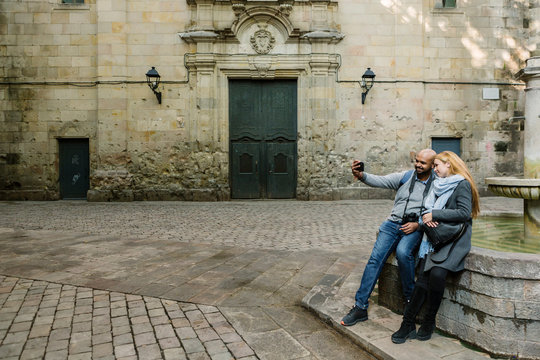 Couple taking selfie with smartphone at Sant Felip Neri Square, Barcelona, Spain