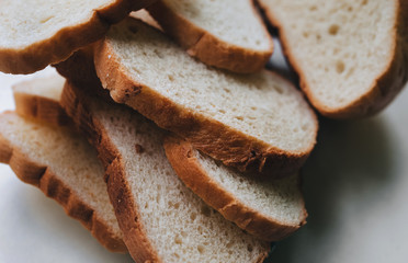 Scattered pieces of white dried bread lie on a white background. Photography, concept.