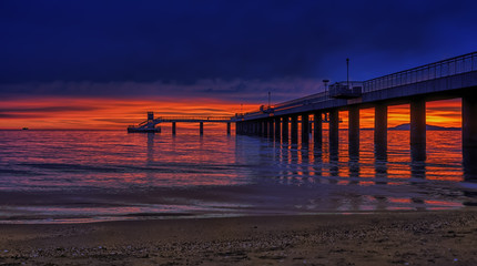 Obraz premium Dramatic sunrise on the beach in Burgas, Bulgaria. Sunrise on the Burgas Bridge. Bridge in Burgas - symbol of the city.