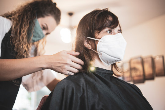Hairdresser using face mask for the covid-19, new normality, social distance, hairdresser and client at client's home with mask cutting hair.