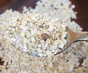 oatmeal lies in a plate and a full spoon of oatmeal on a wooden table