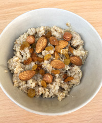 full plate of oatmeal with nuts and raisins on a wooden table