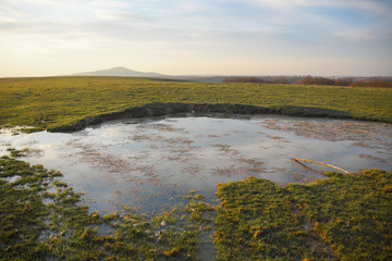 Landscape with green meadow and blue sky with clouds on sunset