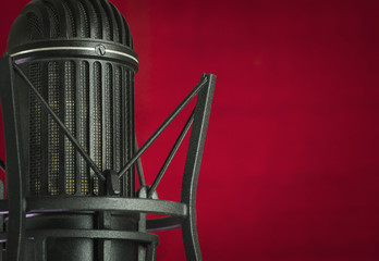 Close up of a retro vocal recording studio microphone in a red background, with copy space