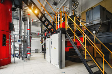 Modern industrial boiler room with chip boiler, fuel supply system pipes and control panels
