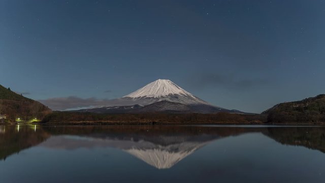 Mt Fuji under full moon with stars and fog at sunrise.