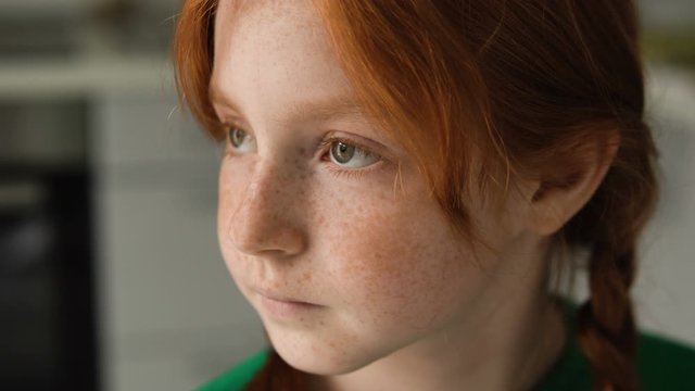 Portrait of thoughtfull serious red-haired little girl. Pretty sad child missing