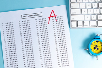 Final exam marked with A+ with red pencil on blue background, top view