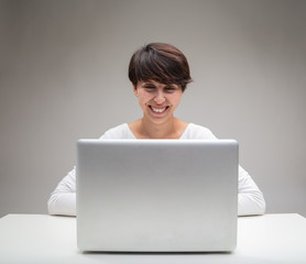 Attractive woman sitting smiling at her laptop