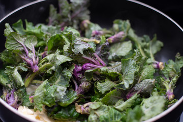 Sautéed kalettes, cooked in butter and garlic in a black pan.