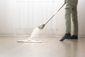 a child in green pants mops the floor in a bright apartment