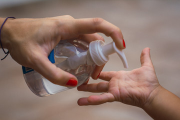 manos de madre colocandole a su hijo alcohol en gel para eliminar bacterias y virus como el covid 19