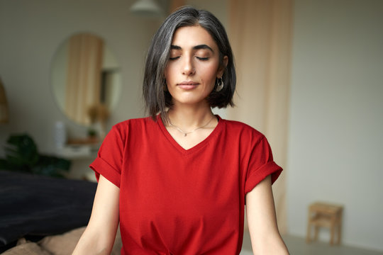 Close up image of beautiful young woman with gray hair and nose ring meditating indoors, using breathing technique, doing pranayamas to prevent stress and level up energy, keeping eyes closed