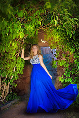 Obraz na płótnie Canvas young girl in a blue dress near the green arch