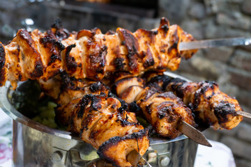 Nature weekend with kebab. Ready chicken skewers on metal skewer. Appetizing meat grilled. Roasted BBQ meat cooked at barbecue. Fried chicken pieces roasting for picnic and street food. Close up