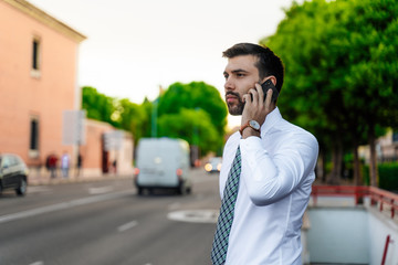 Young business man with white shirt and tie in outdoor city making a phone call