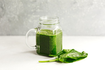 Green smoothie from broccoli, spinach, kiwi and banana on a light background. Eco concept. Healthy green smoothie and ingredients on white - superfoods, detox, diet, health, vegetarian food concept.