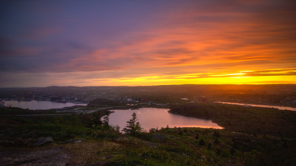 Obraz premium Vibrant sunset over St John's Newfoundland, seen from the top of Signal Hill overlook. Colorful clouds and reflections in the harbour. 